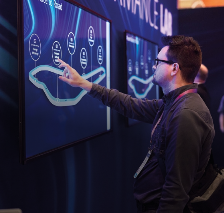Man interacting with a touch screen with a race circuit on it at a convention.