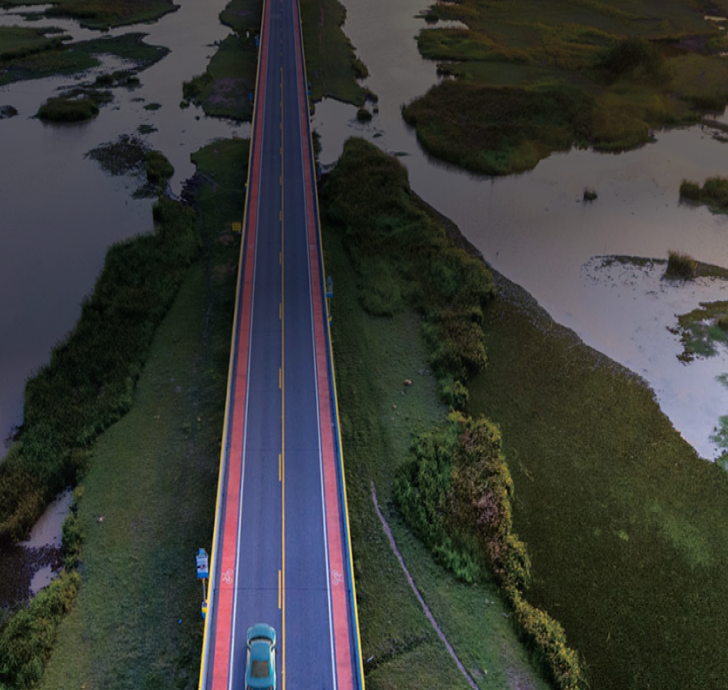 Car traveling on a road through a forest and alongside a lake