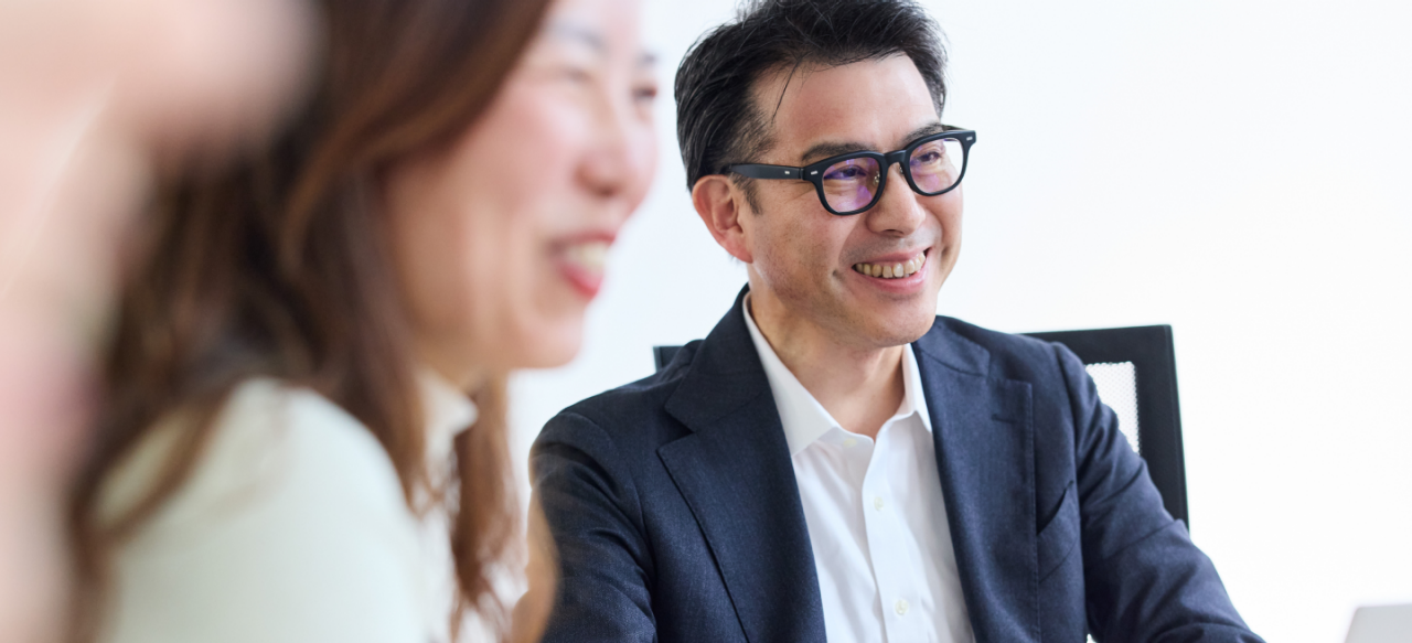 Photo shows a man and a woman smiling at an unseen third person